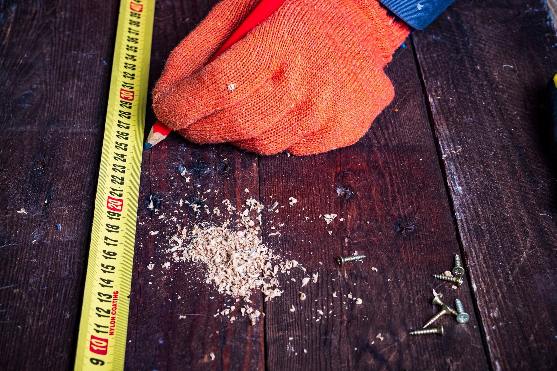 Huincha de medir y guante de trabajo sobre una superficie de madera